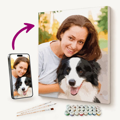 Personalised paint by numbers kit featuring a woman and her dog, with the original photo on a phone, acrylic paints and brushes.